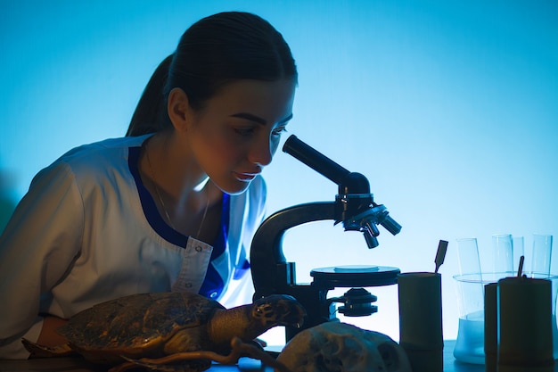 Student girl looking in a microscope, science laboratory concept.