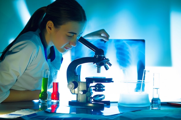 Student girl looking in a microscope, science laboratory concept.