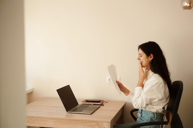 Student girl passed exam and rejoices at high mark Online education and distance learning Woman applicant with laptop holds papers with exam results in his hands and rejoices