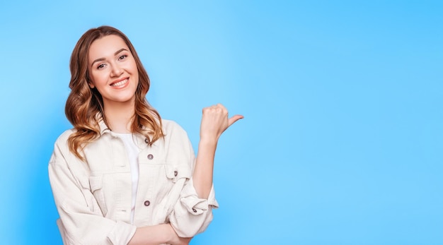 Student girl smiles and points a finger at empty copy space web banner