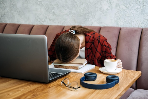 Student girl studying hard exam and sleeping on books in cafe tired girl working