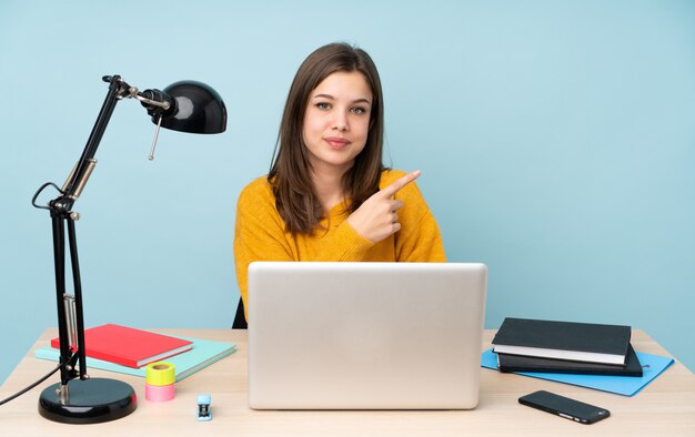 Student girl studying in her house on blue pointing to the side to present a product