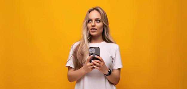 Student girl with a phone in her hands on a yellow background