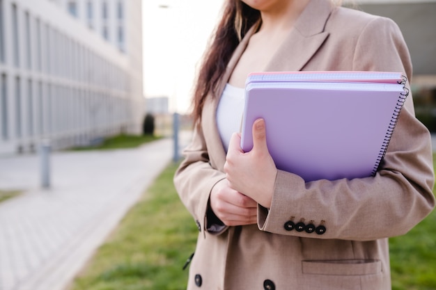 Student holding folders while standing outside college campus education concept