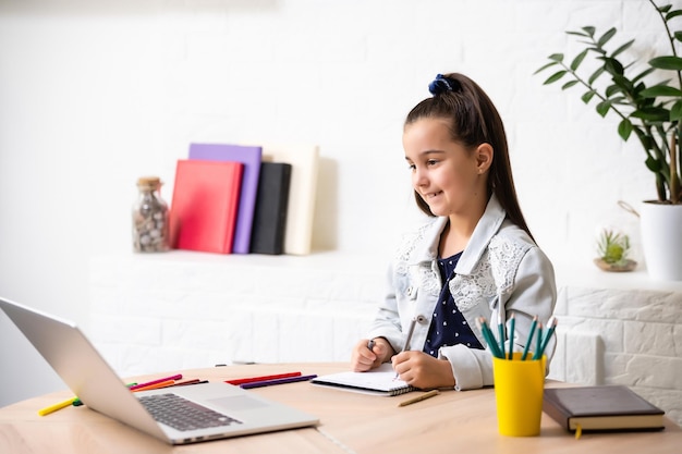 Student little school girl homework on laptop computer silver background