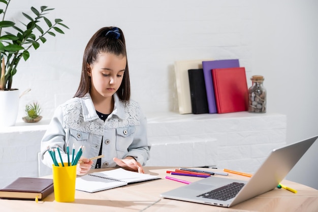 Student little school girl homework on laptop computer silver background