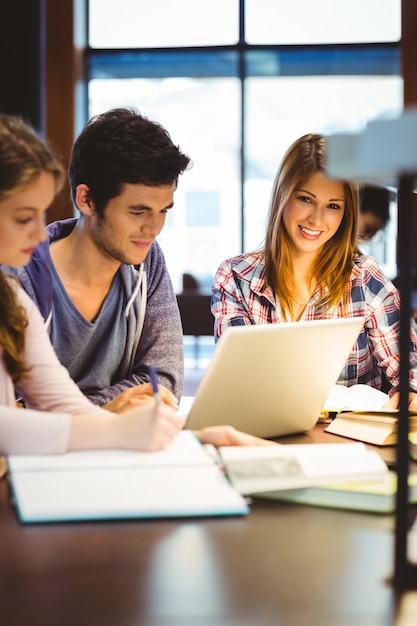 Student looking at camera while studying with classmates