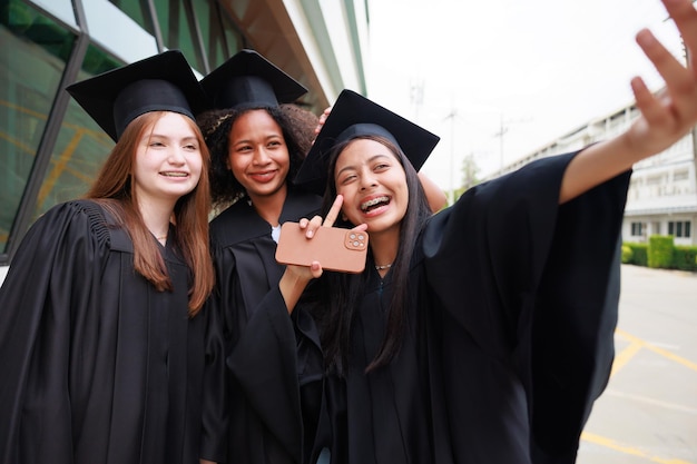 Student wearing gown and making photo by smartphone graduating Happy graduate success and celebration Congratulation