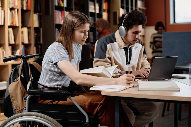 Photo student with disability and her friend at library