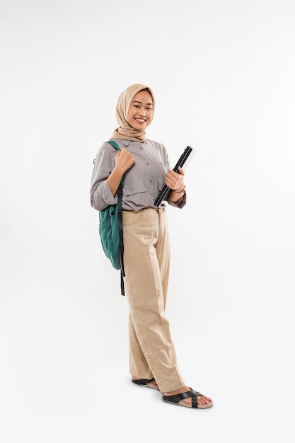 A student with hijab standing bring the green bag and the phone