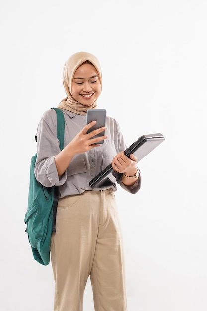 A student with hijab standing with the green bag at her shoulder