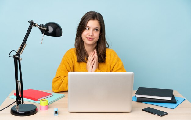 Student woman studying in her house isolated on blue wall scheming something