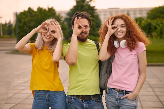 Students gesturing OK near eyes