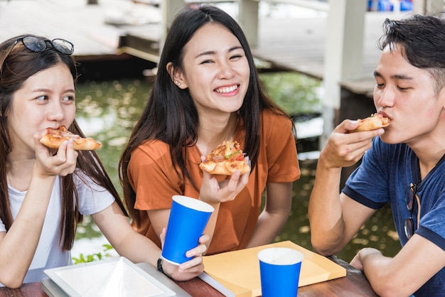 Students group woman and man eating pizza together with cheese delicious having fun and enjoy party at outdoor university, Education concept