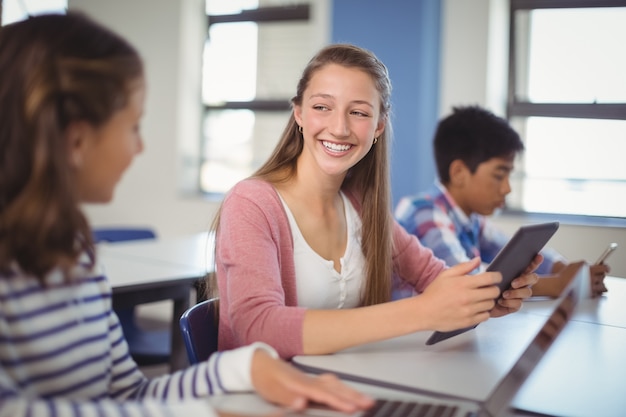 Students using digital tablet and laptop in classroom