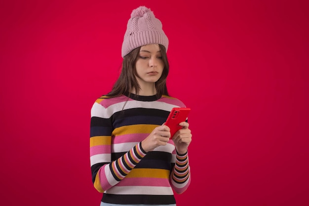 Studio brazilian teenager wearing warm clothes holding a cellphone and with various facial expressions