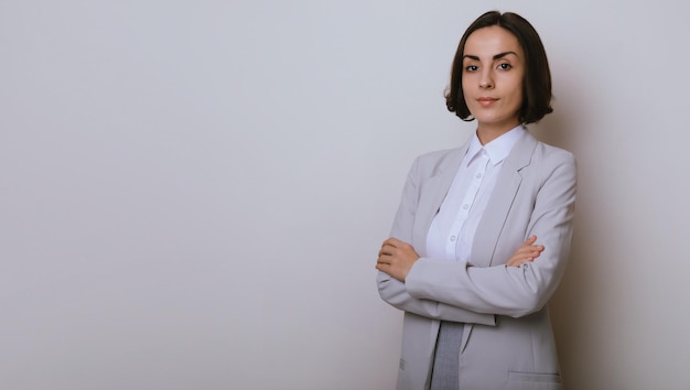 Studio close up portrait of a beautiful businesswoman with crossed arms isolated on gray background