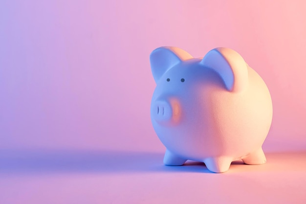 Studio close-up of a white piggy bank with shadow against pink pastel background for copy space as symbol for saving money and finances