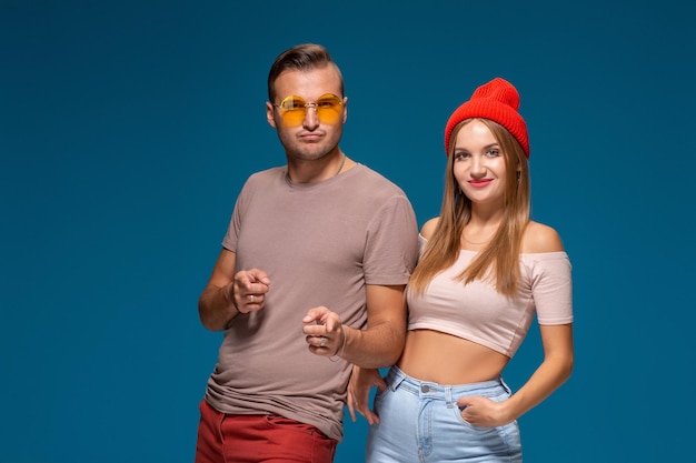 Studio lifestyle portrait of two best friends hipster wearing stylish bright outfits, hats, denim shorts and glasses, going crazy and having great time together.