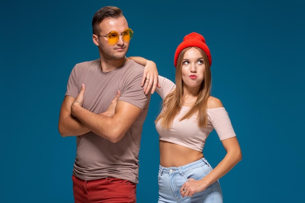 Studio lifestyle portrait of two best friends hipster wearing stylish bright outfits, hats, denim shorts and glasses, going crazy and having great time together.