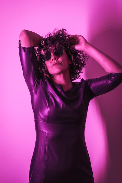 Studio lifestyle a young Caucasian woman enjoying a session with elegant clothes and sunglasses with neon pink light