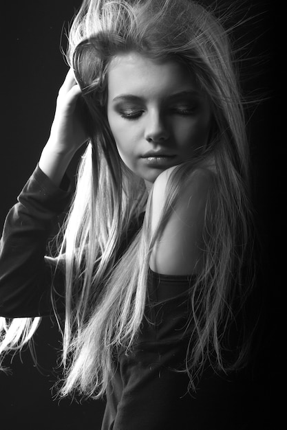 Studio monochrome portrait of a beautiful young woman posing with naked shoulders