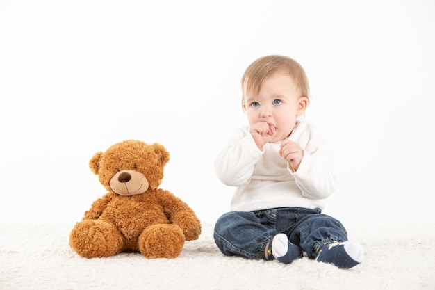 Studio photo Baby with his hand in the mouth with a teddy bear