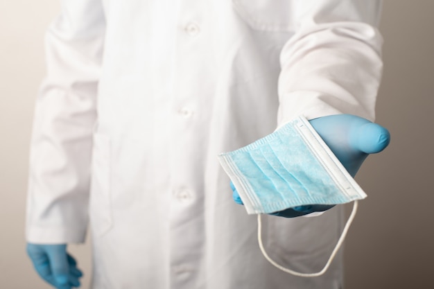 Studio photo of a doctor giving disposal medical mask to a patient. Concept of mandatory wearing protective masks