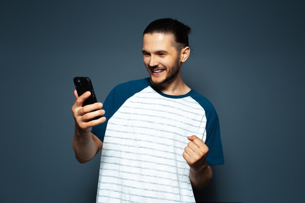 Studio photo of young smiling confident man holding a smartphone