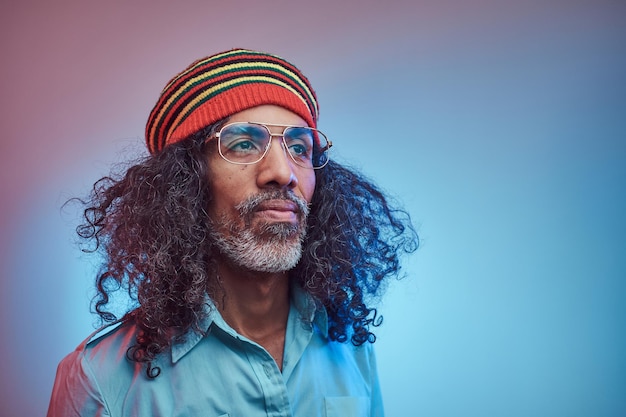 Studio portrait of African Rastafarian male wearing a blue shirt and beanie. Isolated on a blue background.