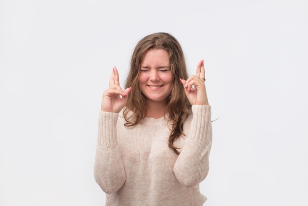 Studio portrait of attractive european woman in red shirt having excited superstitious and naive look