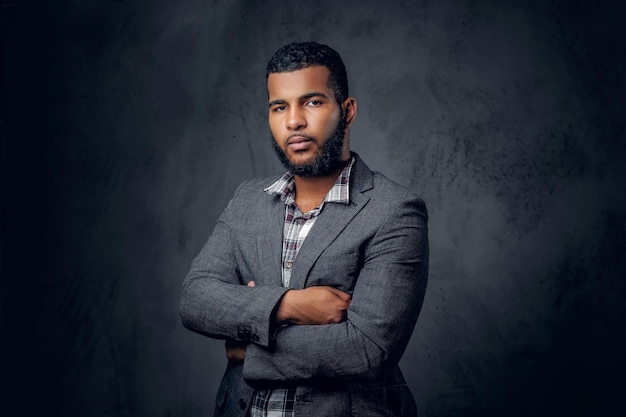 Studio portrait of Black hipster male dressed in a fleece shirt and a jacket posing over grey artistic background.