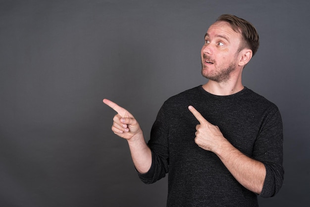 Studio portrait of blonde Caucasian man pointing fingers to copy space