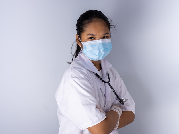 Studio portrait of a female doctor wearing a mask standing on a white background There was a slight light on his face.