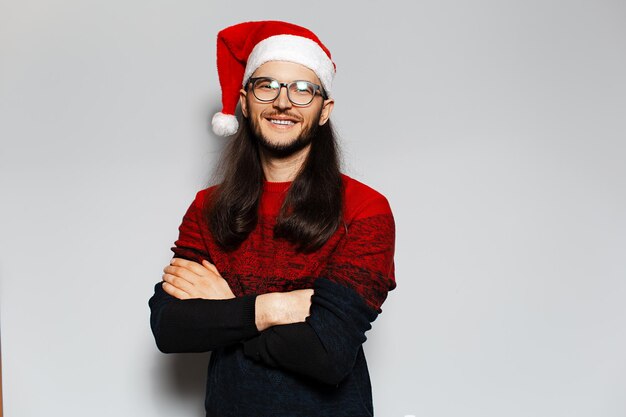 Studio portrait of handsome smiling guy with crossed arms Wearing Santa Claus hat Christmas concept White background