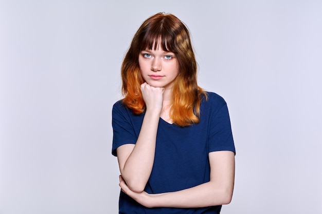 Studio portrait of serious young female looking at camera on light background