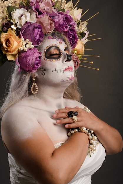 Studio portrait of woman in catrina makeup wearing wedding dress Sugar skull make up