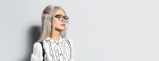 Studio portrait of young blonde pretty girl on white background wearing eyeglasses looking away panoramic banner with copy space