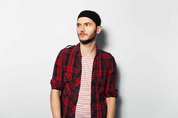 Studio portrait of young cute serious guy wearing red plaid shirt and black headband