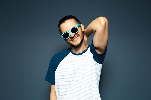 Studio portrait of young handsome man wearing sunglasses Happily smiling