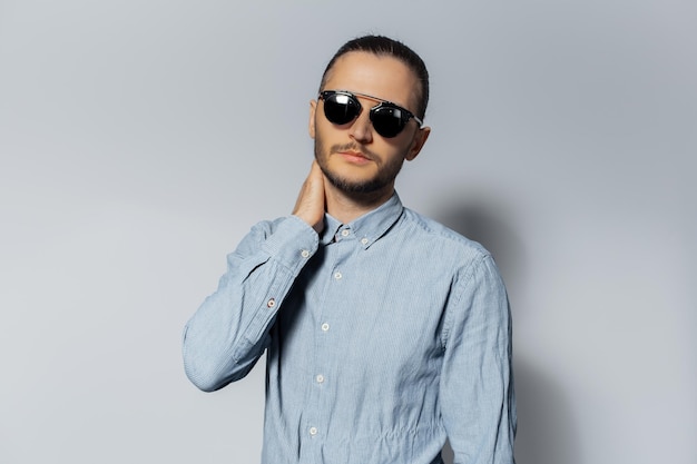 Studio portrait of young man wearing sunglasses and blue shirt on white background