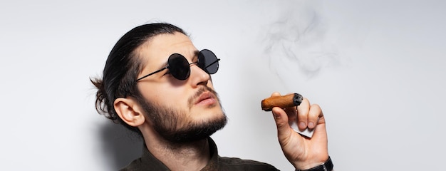 Photo studio portrait of young man with a cigar on white background panoramic banner