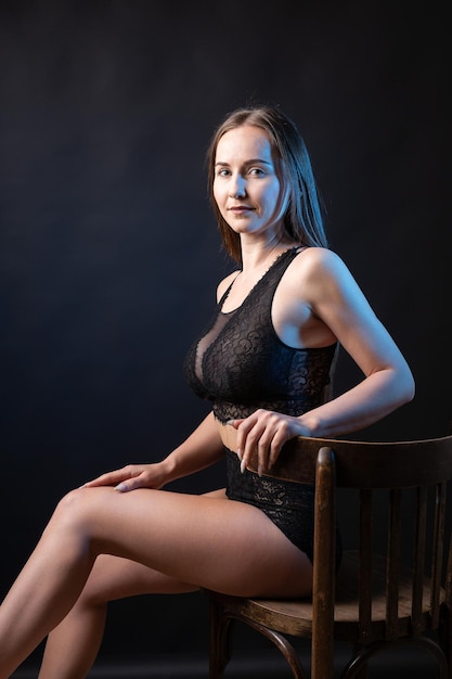 Studio portrait of a young slender girl in lingerie against a black background