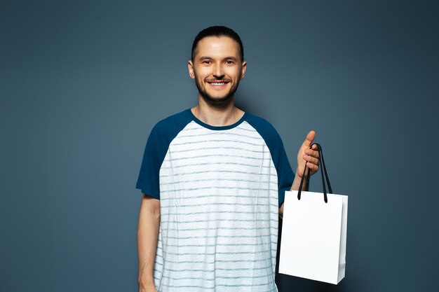 Studio portrait of young smiling man holding a white reusable bag