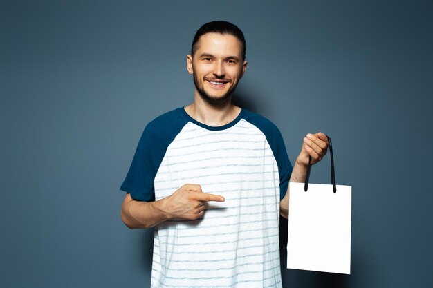 Studio portrait of young smiling man pointing to the white reusable bag