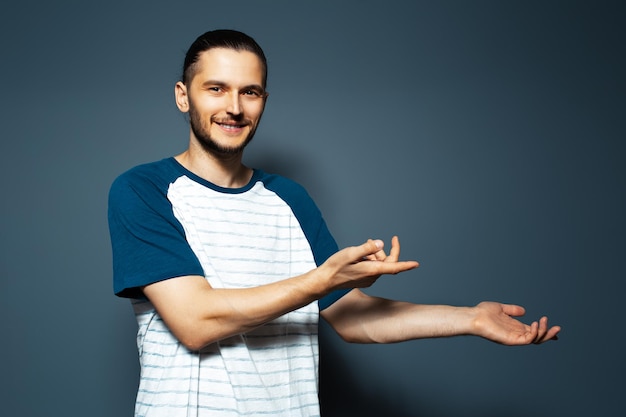 Studio portrait of young smiling man points away on blue background