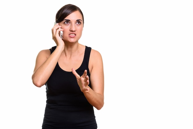 Studio shot of angry woman talking on mobile phone while thinking