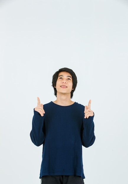 Studio shot of Asian young handsome slim teenager fashion male model in long sleeve shirt standing smiling holding hands pointing fingers on blank copy space presenting product on white background