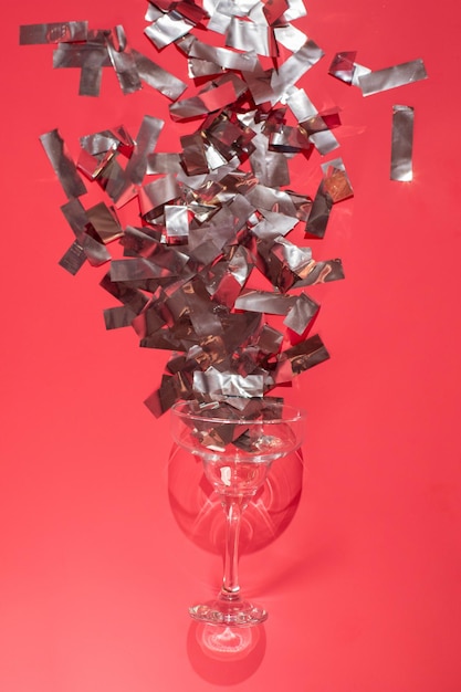 Studio shot of a glass of wine isolated on pink background closeup with celebration confetti