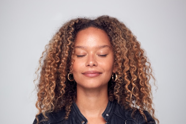 Studio Shot Of Happy Young Woman With Eyes Closed Daydreaming